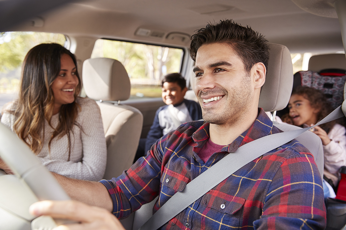 Mother turns around to her children in the back seat of car while her husband drives