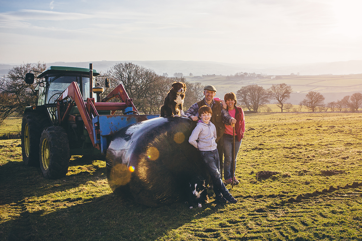 Environmental portrait of a two generation family of farmers with their tractor